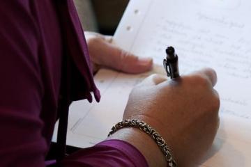 Hand som håller i en penna och skriver på ett papper