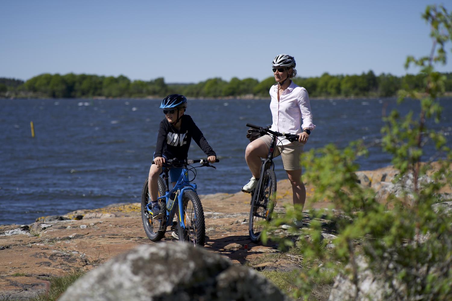 Familj som är på cykeltur i Karlskrona skärgård, spanar ut över havet från en klippa.