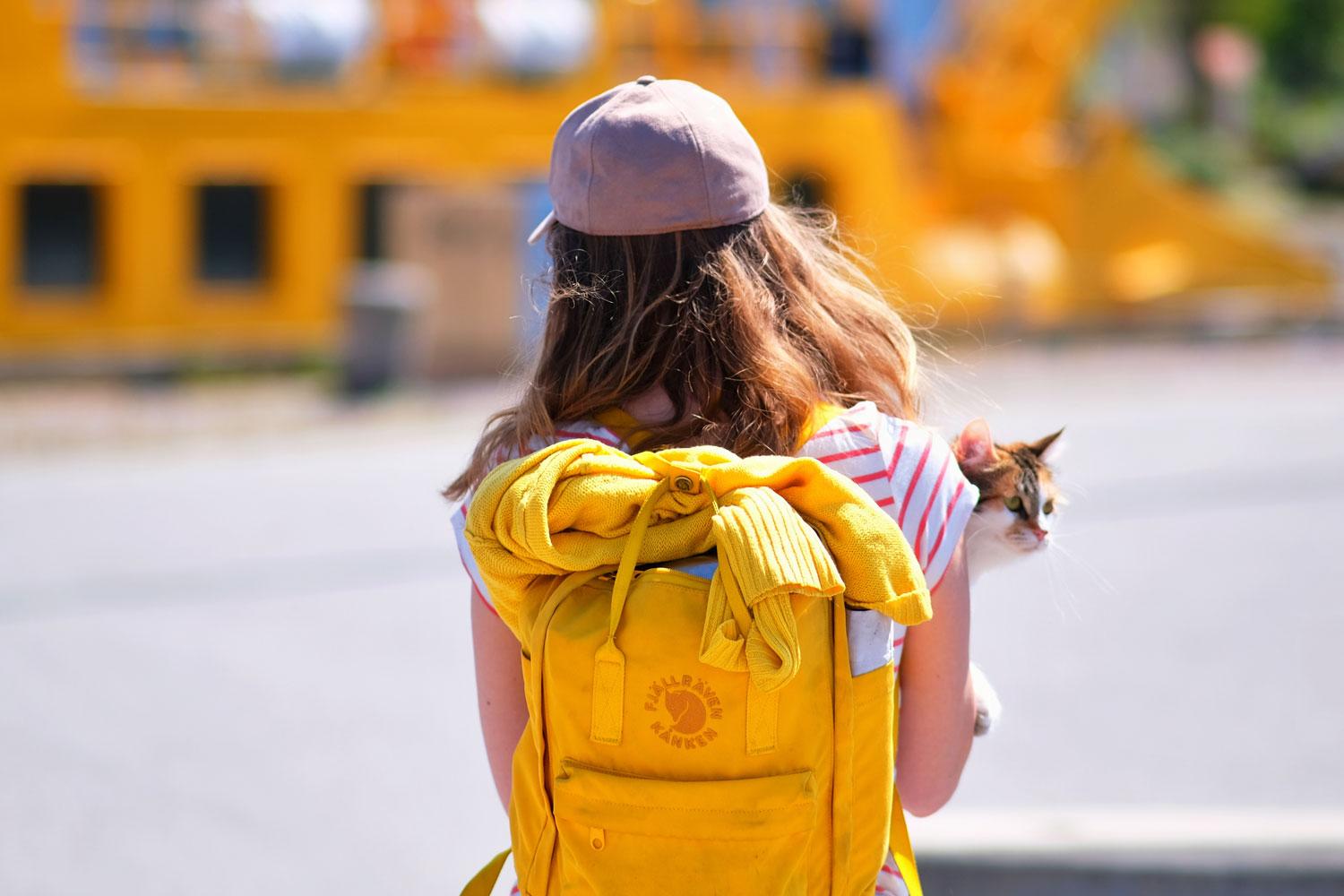 flicka med gul ryggsäck