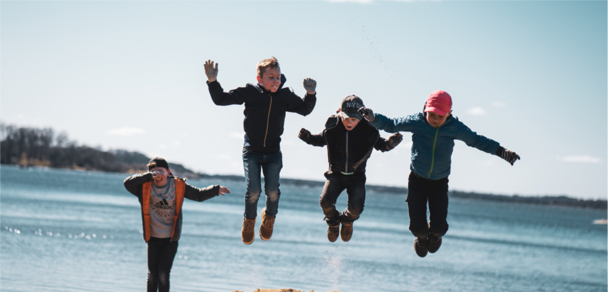 Barn som hoppar vid havet