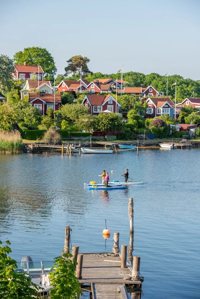 Tre kvinnor paddlar i borgmästarefjärden framför Brändaholm