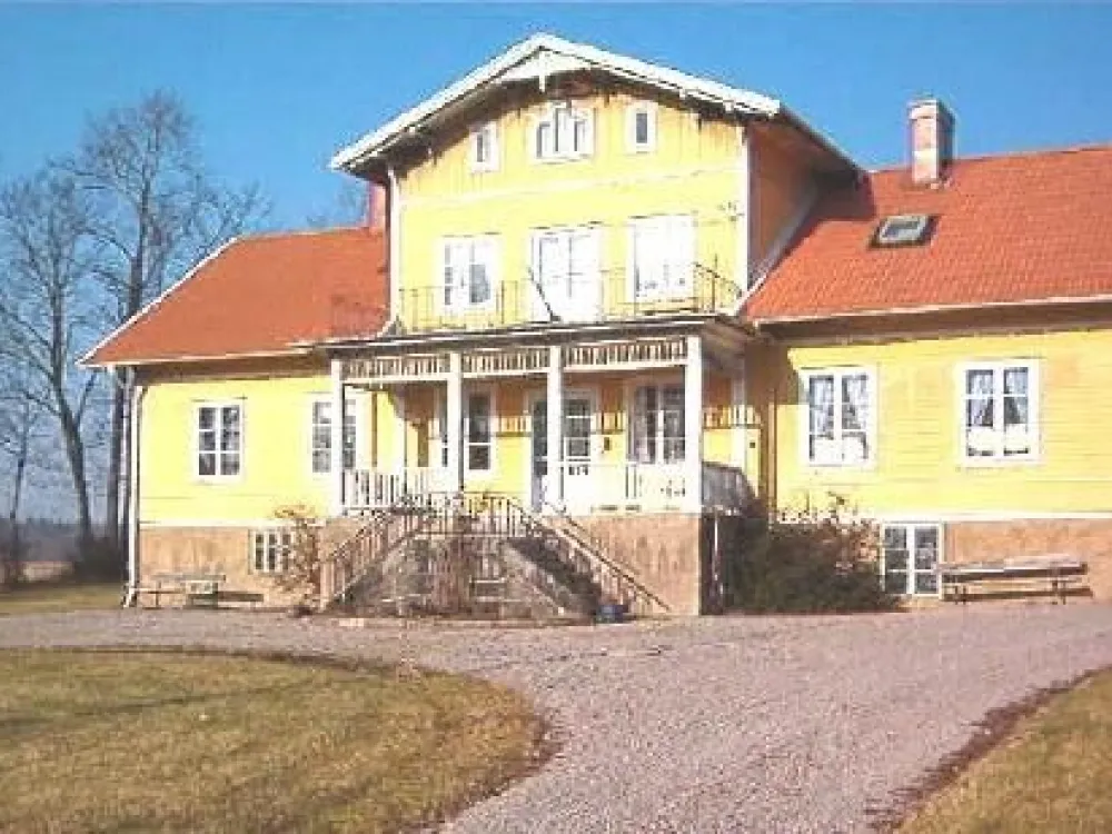En bild på ett stort gult trähus med rött tegeltak