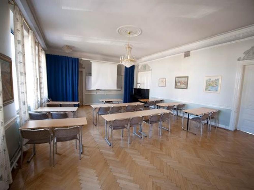 vitt konferensrum med några bord, stolar och blåa gardiner