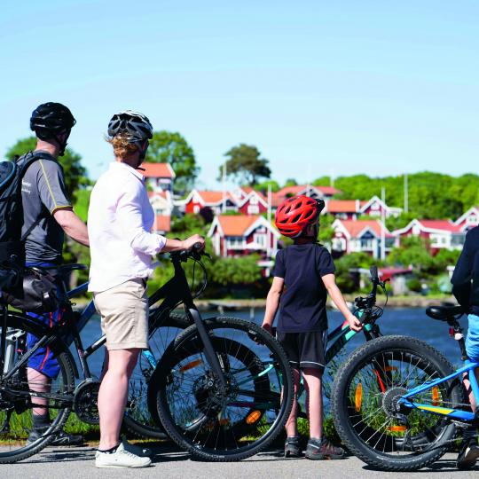 Familj som står och tittar på Brändaholm med sina cyklar